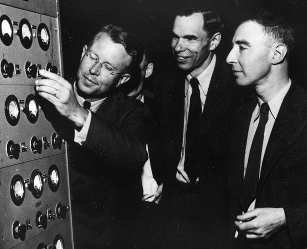 Lawrence, Glenn T. Seaborg, and J. Robert Oppenheimer operate a cyclotron for the cameras in a postwar photograph. Small historical detail (literally): one can find this photograph sometimes flipped on its horizontal axis. Which is the correct orientation? One can take guesses based on rings, handedness, etc., but the copy of the scan that I have has sufficient resolution that you can read the dials, which I think resolves the question. Credit: Emilio Segrè Visual Archives. 